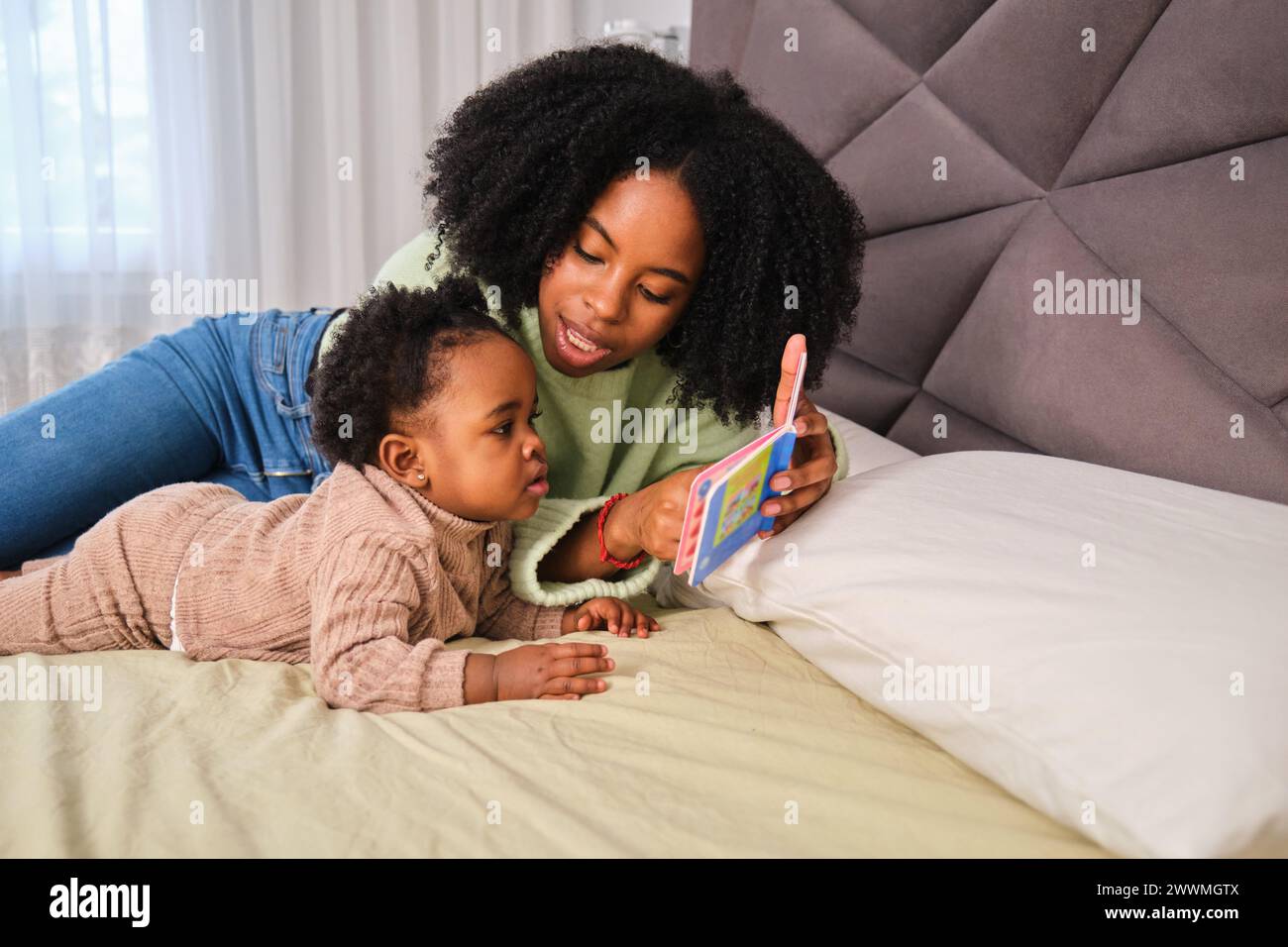 Mère cubaine lisant un livre pour enfants à sa petite fille. Banque D'Images