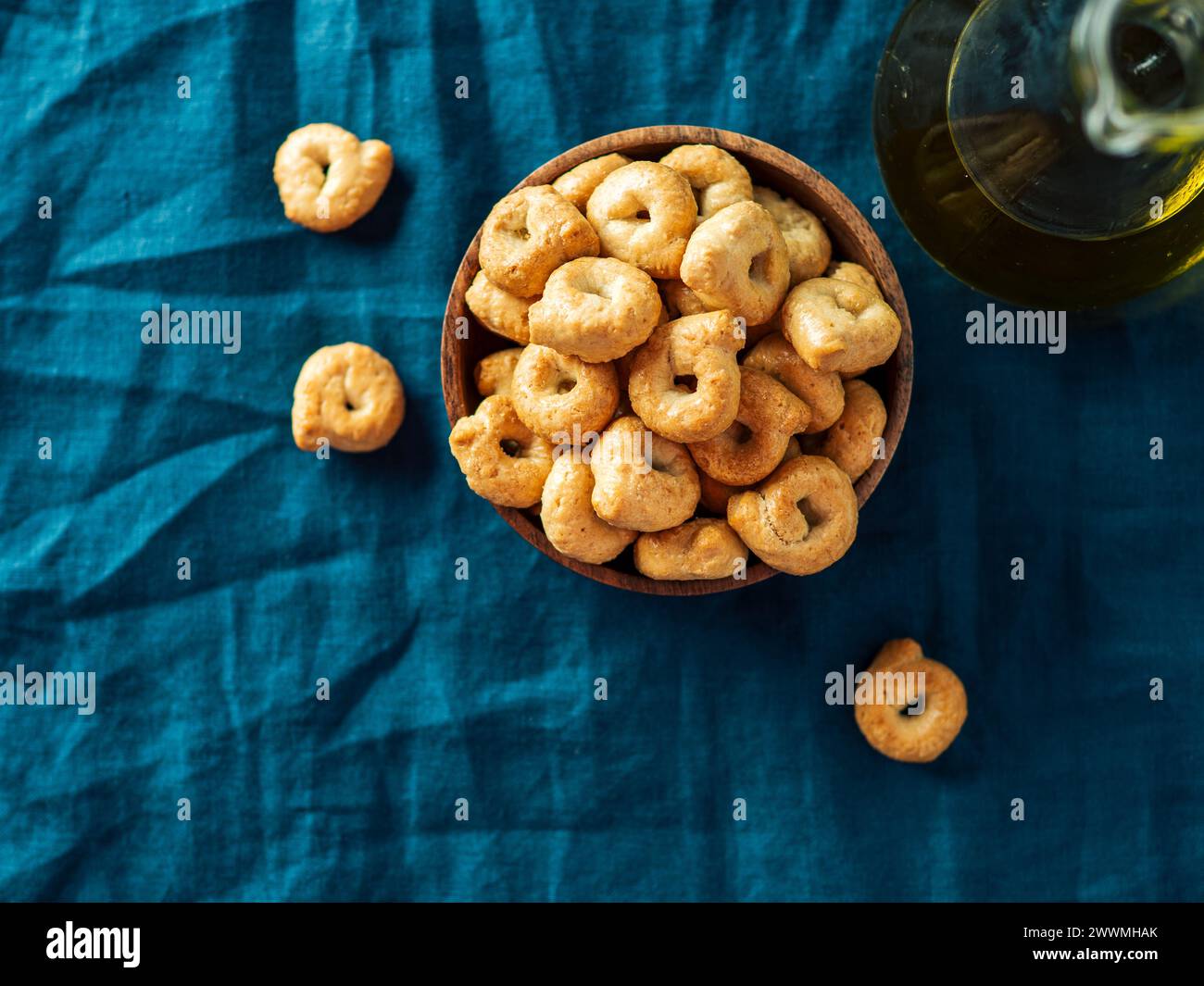 Taralli ou tarallini de snack italien traditionnel dans un bol en bois sur fond de serviette en lin bleu foncé. Plan rustique de taralli apéritif avec espace de copie. Vue de dessus ou pose à plat. Banque D'Images