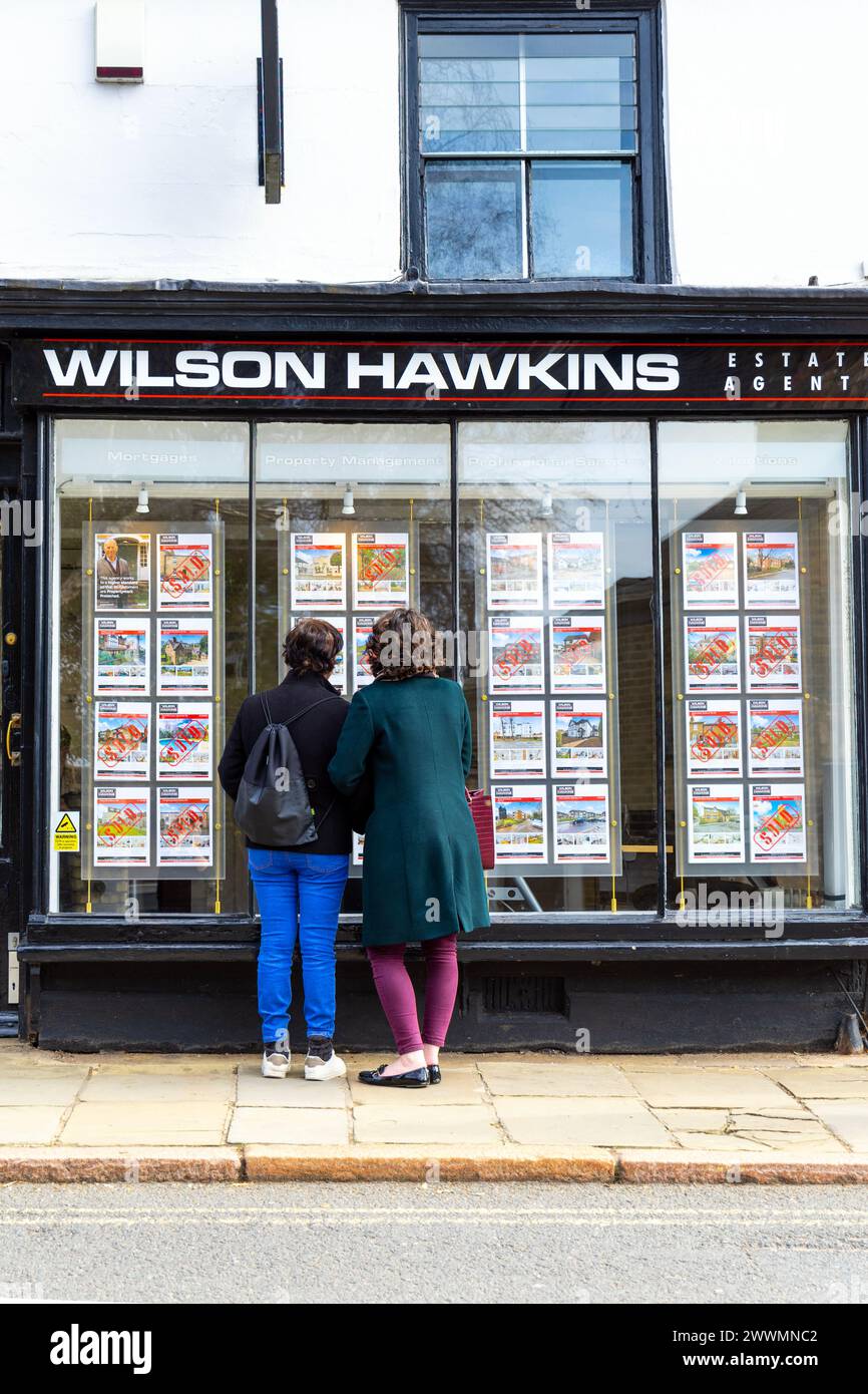 Femmes regardant des affiches de propriété à la vitrine d'un agent immobilier, Harrow, Londres, Angleterre Banque D'Images