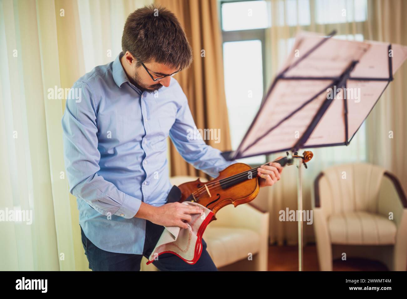 Homme jouant du violon à la maison. Il nettoie son instrument. Banque D'Images