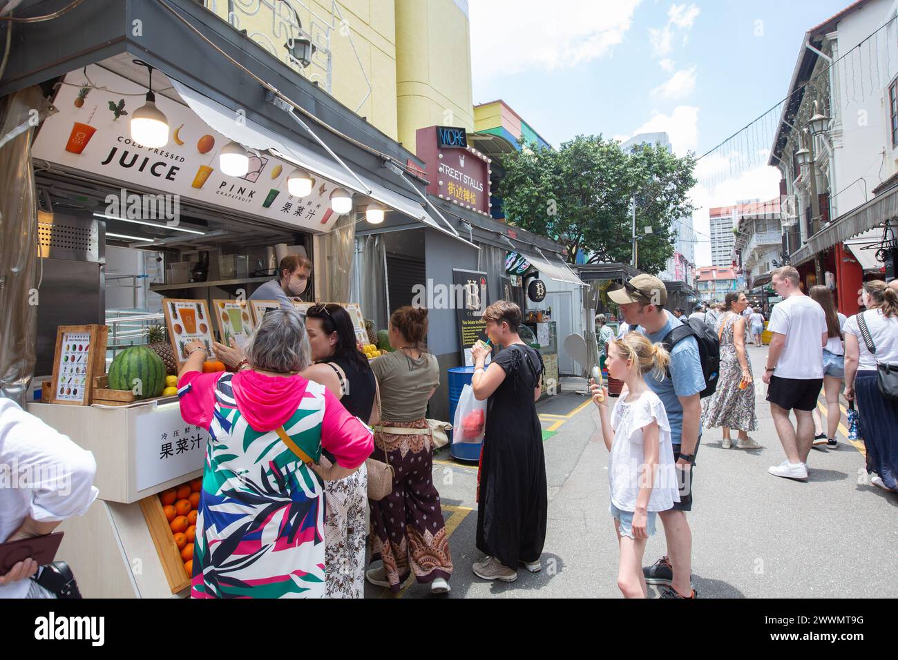 Par temps chaud, un groupe de touristes font la queue devant un stand de jus de fruits frais pour s'hydrater. Voyageurs errant dans la rue. Chinatown, Singapour. 2024. Banque D'Images