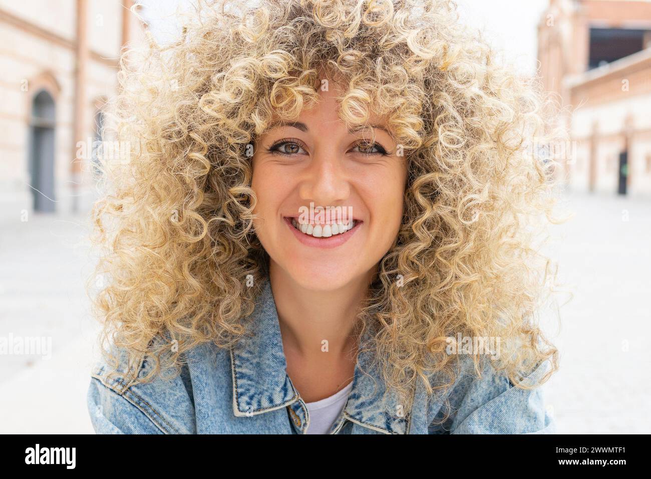 Portrait d'une jeune femme caucasienne souriante aux cheveux blonds bouclés Banque D'Images