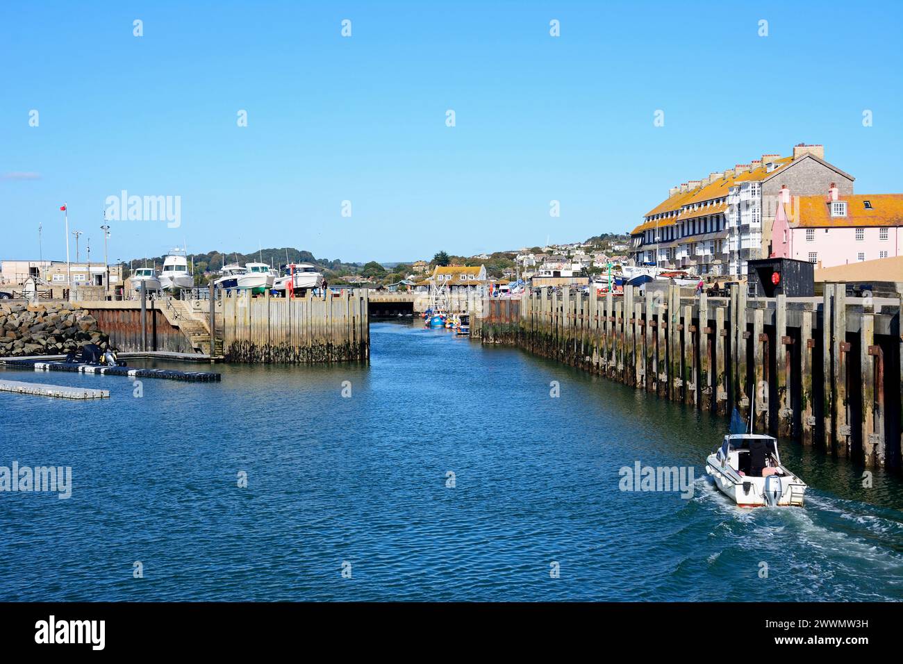 Bateau entrant dans le port avec la porte de la Sluice et les bâtiments de la ville à l'arrière, West Bay, Dorset, Royaume-Uni, Europe. Banque D'Images