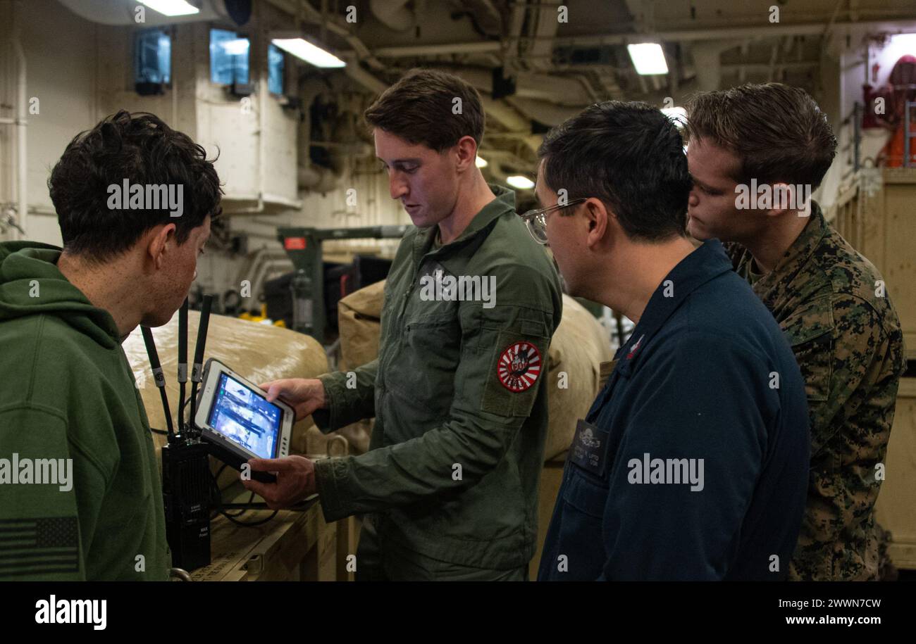 OCÉAN PACIFIQUE (17 février 2024) Sergent Joseph Dutcher, centre gauche, de East Bridgewater, Massachusetts, affecté au bataillon logistique de combat 31, élimination d'explosifs (EOD), 31st Marine Expeditionary Unit (MEU), montre comment contrôler une plate-forme robotique lors d'une démonstration d'élimination d'explosifs (EOD) dans la zone de stockage de véhicules du porte-avions d'assaut amphibie déployé à l'avant USS America (LHA 6), tout en menant des opérations de routine dans l'océan Pacifique, le 17 février. America, navire principal de l'America Amphibious Ready Group, opère dans la zone de la 7e flotte américaine Banque D'Images