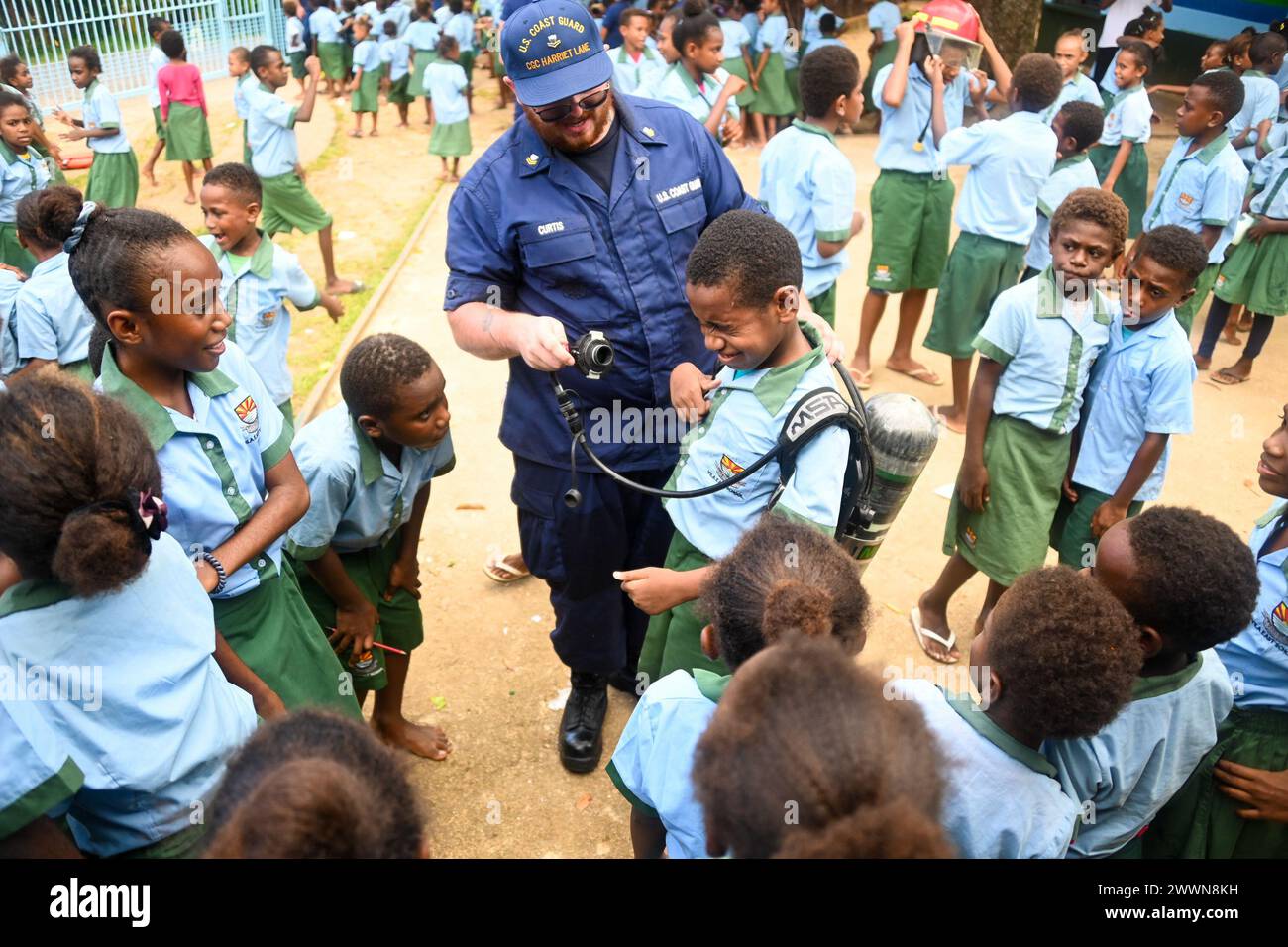 Le second maître de 2e classe de la Garde côtière américaine Michael Curtis, un membre d'équipage du Cutter de la Garde côtière américaine Harriet Lane (WMEC 903), montre à un écolier de Vila East un appareil respiratoire autonome à Port Vila, Vanuatu, le 29 février 2024. Les membres de l’équipage de Harriet Lane ont visité deux écoles à Port Vila pour renforcer les liens avec la communauté locale et partager les connaissances culturelles entre les deux pays. Garde-côtes Banque D'Images