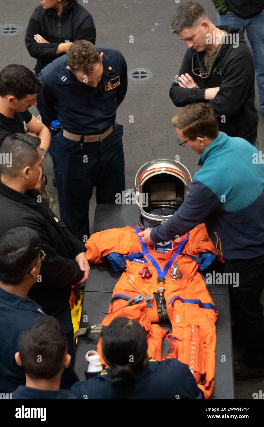 Des marins de l'US Navy affectés à la Fleet Surgical Team 3 et aux affiliés de la NASA inspectent la combinaison d'entraînement Orion Crew Survival Systems dans la baie du hangar à bord du navire de transport amphibie de classe San Antonio USS San Diego (LPD 22) pendant le test de récupération en cours 11, le 22 février 2024. En préparation de la mission Artemis II avec équipage de la NASA, qui enverra quatre astronautes à Orion au-delà de la Lune, la NASA et le ministère de la Défense mèneront une série de tests pour démontrer et évaluer les processus, les procédures et le matériel utilisés dans les opérations de récupération pour les missions lunaires avec équipage. L'US Navy a beaucoup d'uniqu Banque D'Images