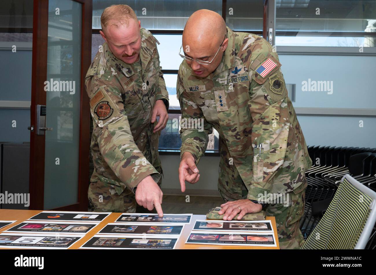 Le lieutenant Col. Ryan Sheridan, directeur du laboratoire de la 21e escadron dentaire, à gauche, montre des photos de pilotes de chasse à la U.S. Space Force Lt. Gen. David N. Miller, Jr., commandant du commandement des opérations spatiales, lors d'une visite de la clinique dentaire Peterson sur la base spatiale Peterson, Colorado, le 29 février 2024. Les pilotes de chasse sur les photos ont tous été victimes de dommages au visage causés par des masques faciaux de stock, ce qui a conduit à des problèmes tels que rougeurs, gonflements et saignements. La 21e clinique dentaire a un rôle à jouer dans la résolution de ce problème en utilisant des scanners faciaux pour concevoir et imprimer en 3D des inserts de masque facial qui empêchent les dommages et s'adaptent au pi Banque D'Images