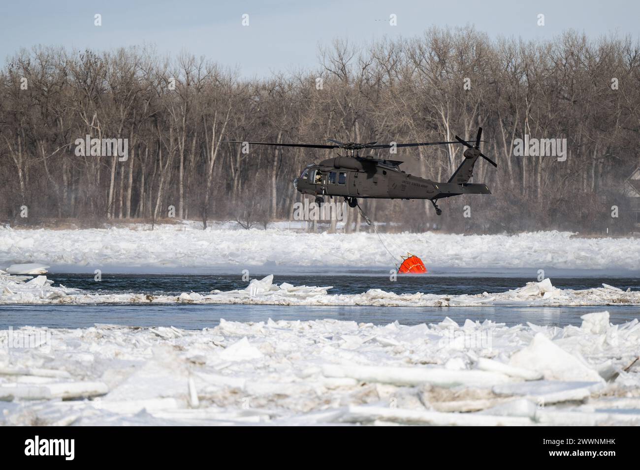 Un hélicoptère UH-60 Black Hawk de la Garde nationale du Dakota du Nord remplit un seau Bambi de 660 gallons d'eau pour tomber sur un embâcle sur la rivière Missouri à Bismarck, Dakota du Nord, le 29 février 2024, pour briser la glace et prévenir les inondations. Plus de 70 000 gallons d'eau ont été lâchés en 4 heures. Garde nationale Banque D'Images