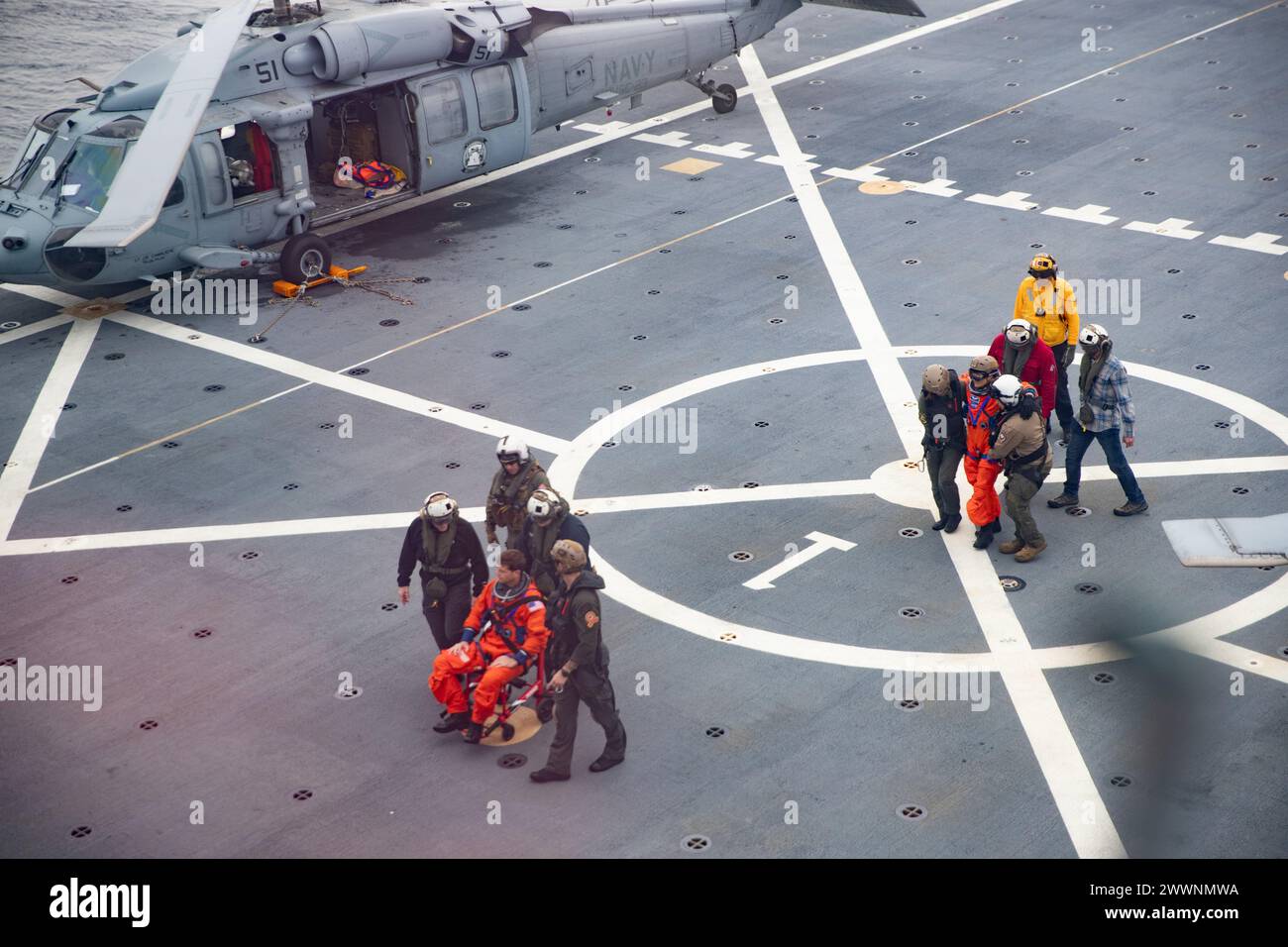 Marins de l'US Navy affectés au navire de transport de classe San Antonio USS San Diego (LPD 22) et les “wildcards” de Helicopter Sea combat Squadron 23 guident l’astronaute de la NASA le Capt. Reid Wiseman et l’astronaute de la NASA Christina Hammock Koch vers les installations médicales du navire depuis le pont d’envol pendant l’entraînement en cours pour le test de récupération 11 de la NASA, 25 février 2024. En préparation de la mission Artemis II de la NASA, qui enverra quatre astronautes à Orion au-delà de la Lune, la NASA et le ministère de la Défense mèneront une série de tests pour démontrer et évaluer les processus et la procédure Banque D'Images