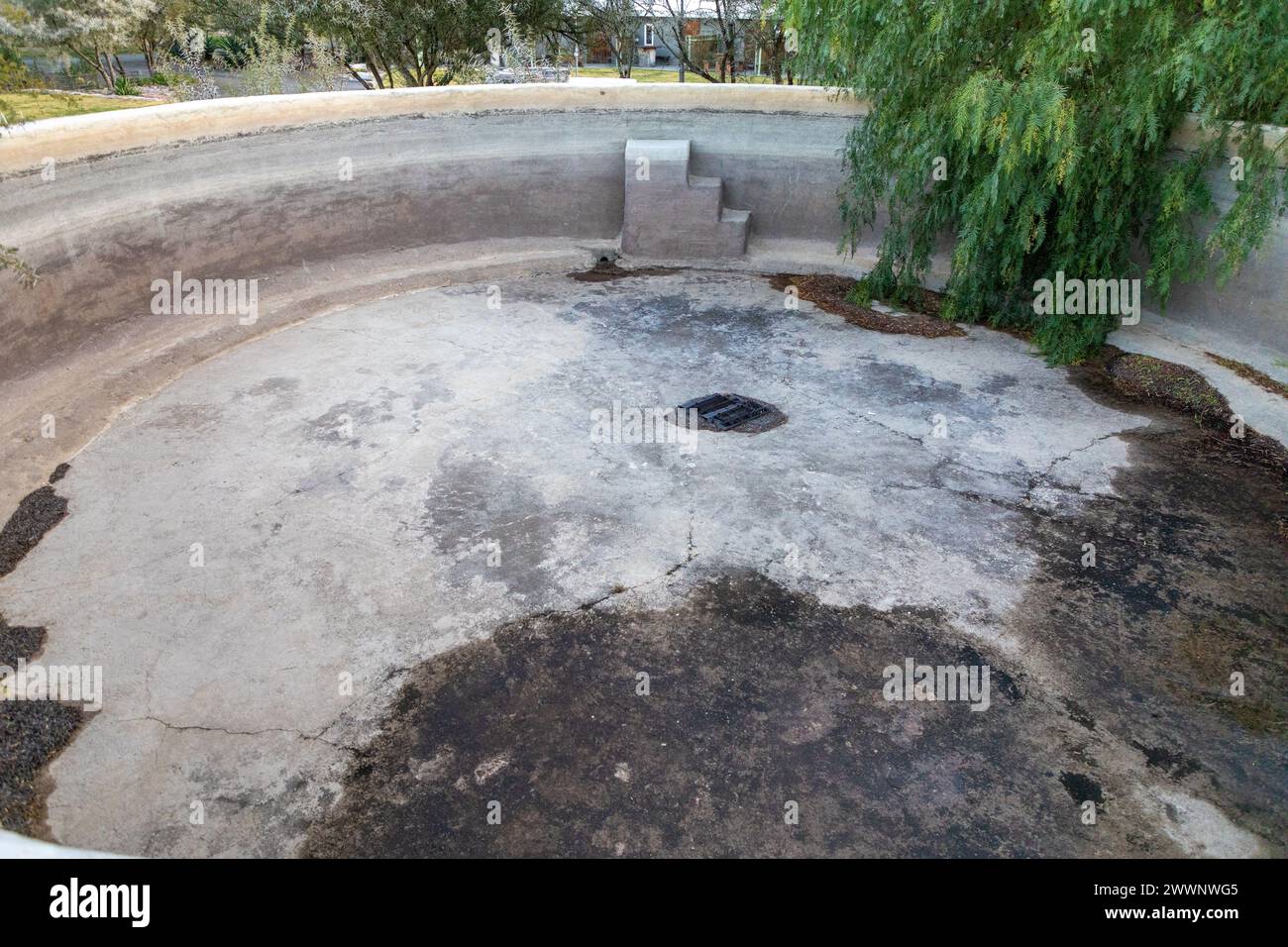 Partie d'une grande piscine ronde vide en béton. Au fond de la piscine il y a des fissures. Concept pour piscines qui fuient. Banque D'Images