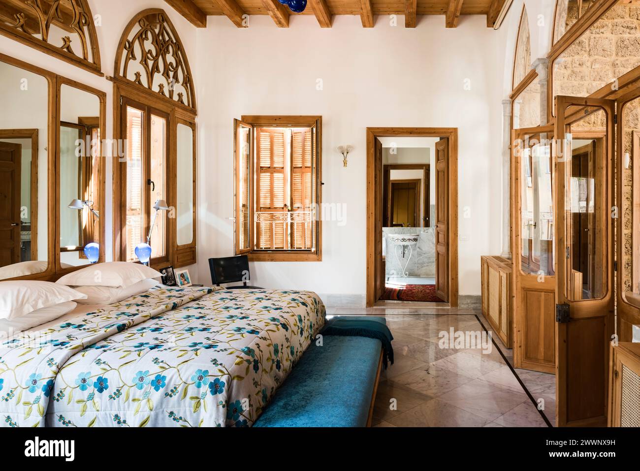 Couvre-lit floral sur lit double avec fenêtres en éventail arabe dans un appartement de luxe à Beyrouth, Liban. Banque D'Images
