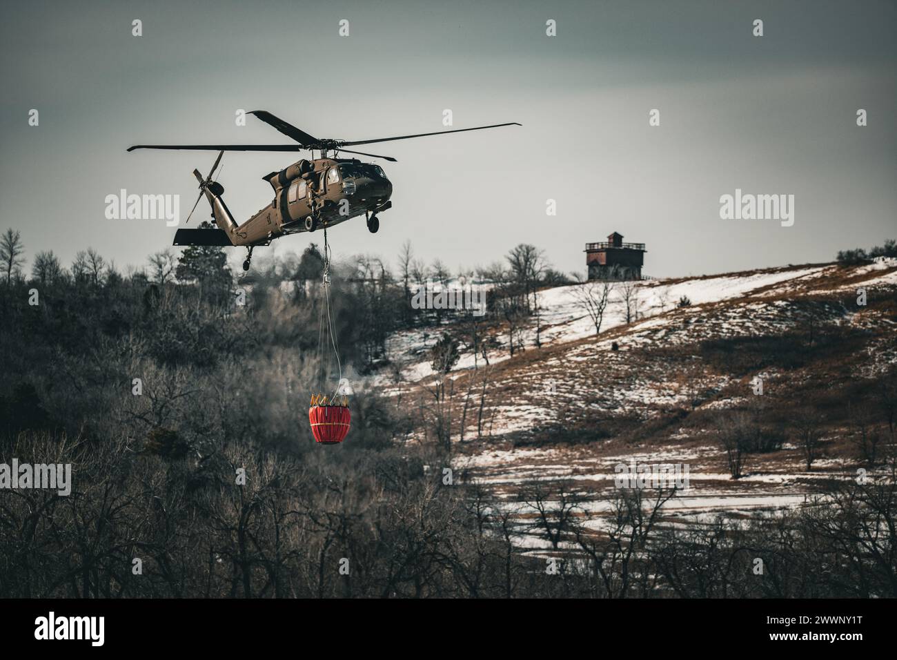 Un hélicoptère Black Hawk UH-60 de la Garde nationale du Dakota du Nord transporte 660 gallons d'eau dans un seau Bambi pour tomber sur un embâcle sur la rivière Missouri à Bismarck, Dakota du Nord, le 29 février 2024, pour briser la glace et empêcher les inondations. Plus de 70 000 gallons d'eau ont été lâchés en 4 heures. Garde nationale Banque D'Images