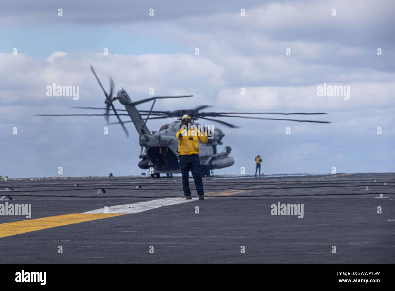 Un marin de l'US Navy dirige des hélicoptères CH-53E Super Stallion avec le Marine Heavy Helicopter Squadron (HMH) 462, Marine Aircraft Group 16, 3rd Marine Aircraft Wing, sur le pont d'envol de l'USS Abraham Lincoln (CVN 72) dans l'océan Pacifique, le 13 février 2024. Le HMH-462 transportait des passagers de la Naval Air Station North Island, Coronado, à l'Abraham Lincoln, un porte-avions de la classe Nimitz, et fournissait un soutien d'assaut pour les opérations de routine dans la zone d'opérations de la troisième flotte. Atterrir sur un porte-avions était une occasion rare pour les Marines du HMH-462, alors que les CH-53E Super Stallions se déployaient à eux-mêmes Banque D'Images