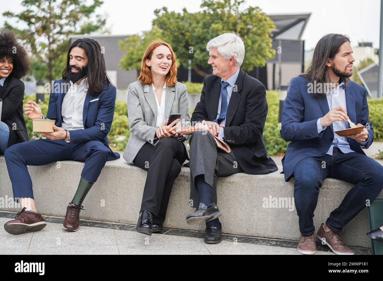 Des gens d'affaires de différentes ethnies et âges mangeant et discutant ensemble en plein air à la pause déjeuner - concept de réunion et d'entreprise Banque D'Images