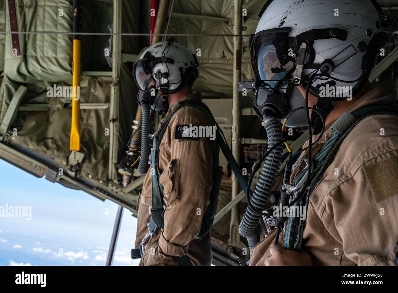 Les maîtres de chargement du corps des Marines des États-Unis affectés au Medium Tiltrotor Squadron 261, ou VMM-261 (REIN), regardent à l'arrière d'un avion cargo USMC KC-130J Hercules au-dessus de l'Afrique de l'est, le 27 février 2024. Le KC-130J est souvent utilisé pour ravitailler les zones de bataille, fournir un centre de soutien aérien direct, insérer des troupes de groupe et effectuer des opérations d'évacuation sanitaire. Armée de l'air Banque D'Images