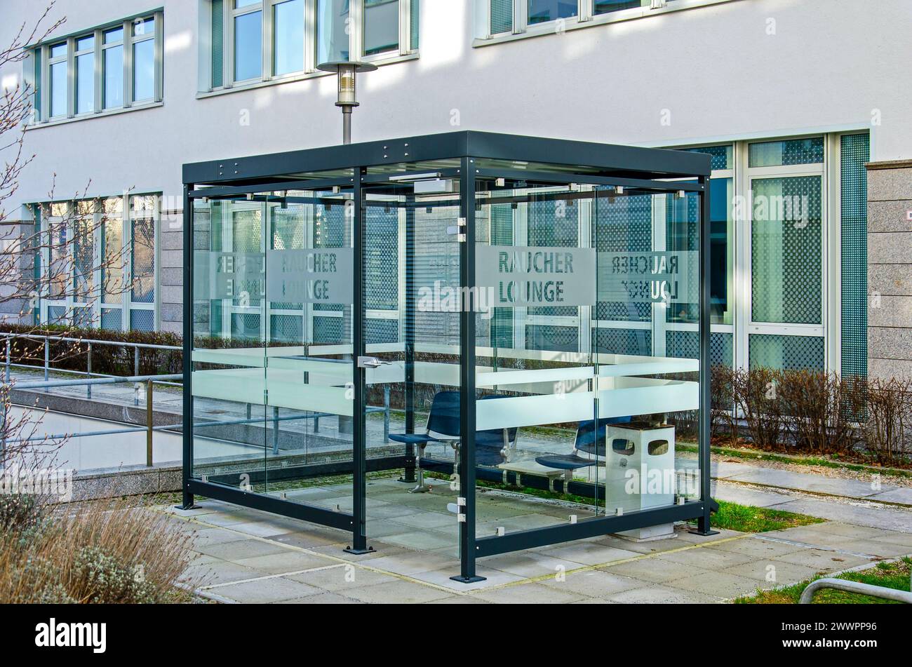 Berlin, Allemagne, 7 mars 2024 : petit abri en verre entre les immeubles de bureaux, servant de salon pour fumeurs Banque D'Images