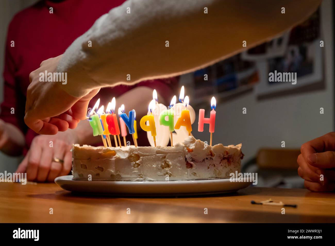 mains avec allumettes allumant des bougies vax sur le gâteau d'anniversaire Banque D'Images