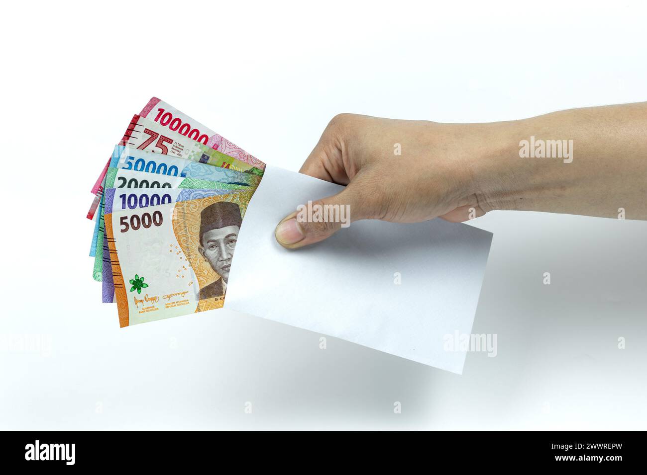 Main de l'homme asiatique tenant pile de billets de banque Rupiah ou IDR à l'intérieur de l'enveloppe blanche sur fond blanc Banque D'Images