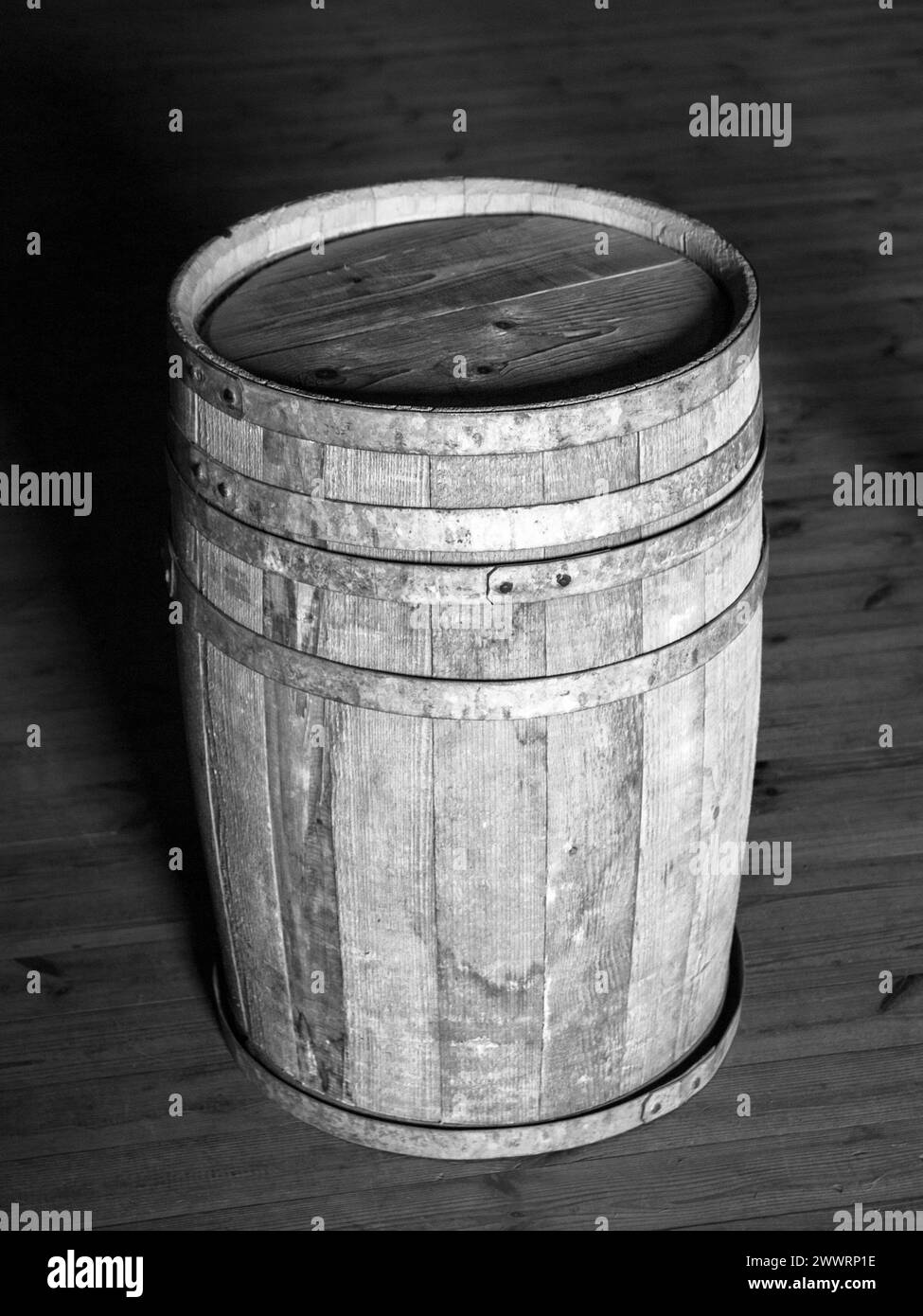 Vieux tonneau en bois debout sur le plancher en bois. Image en noir et blanc. Banque D'Images
