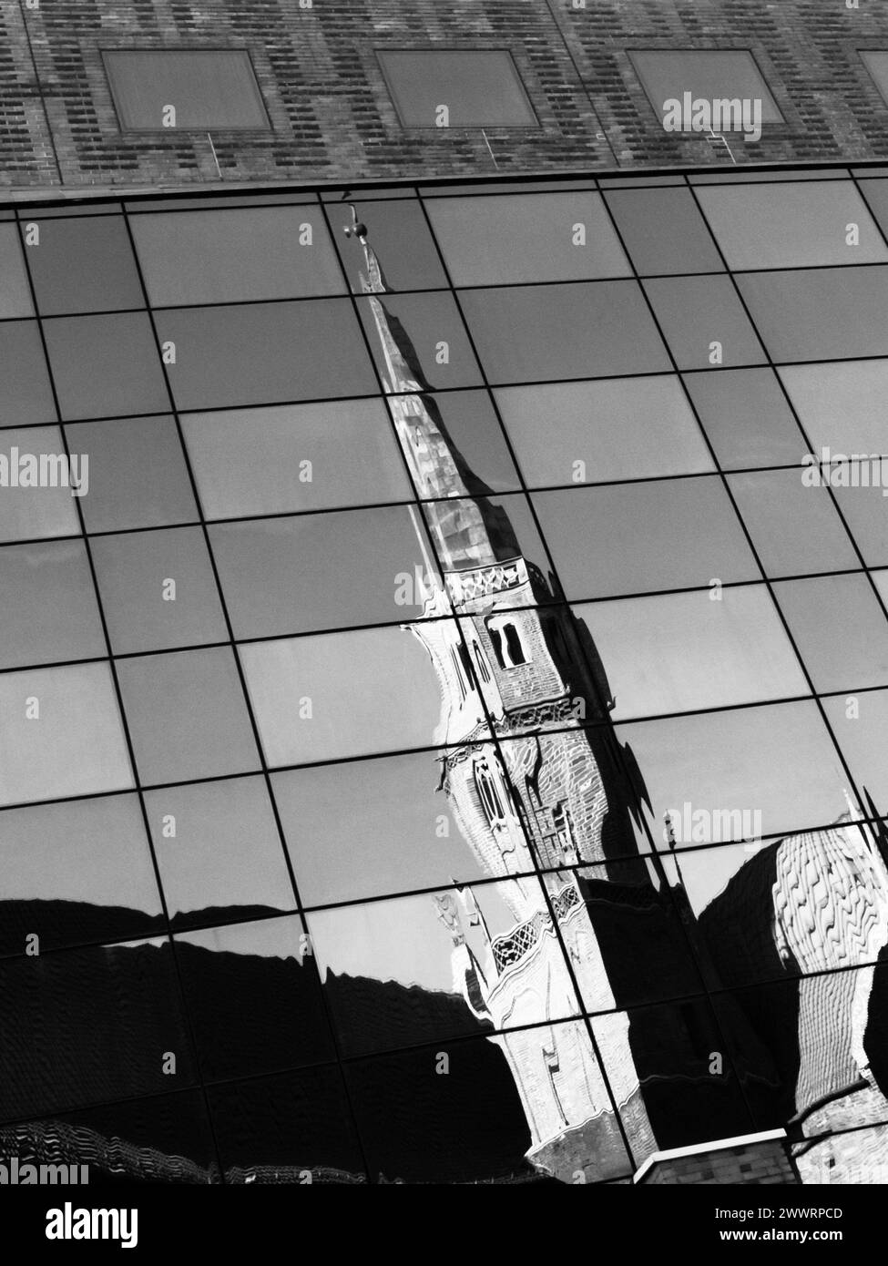 Contraste de l'architecture moderne et historique. Reflet de la vieille tour de l'église dans le mur de verre du bâtiment moderne. Image en noir et blanc. Banque D'Images