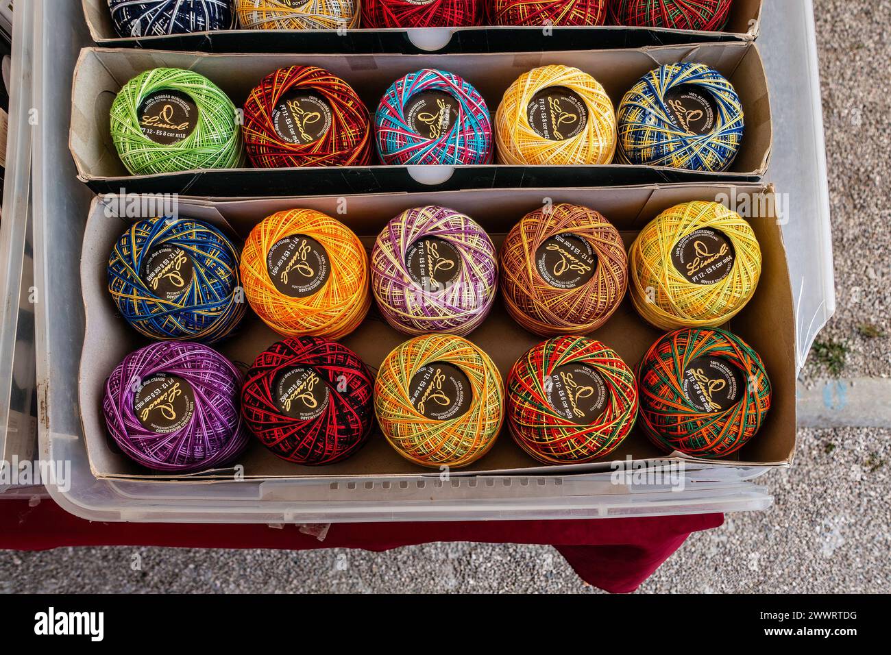 Boules de fil colorées fabriquées à la main exposées dans des boîtes en carton au stand de marché extérieur à Quarteira, Portugal. Banque D'Images
