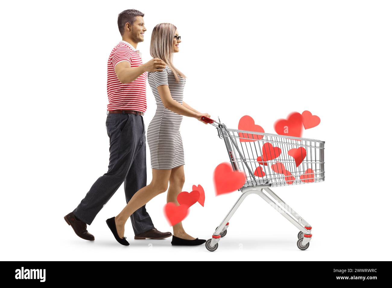 Plan de profil d'un jeune couple marchant et poussant un chariot avec des cœurs rouges à l'intérieur isolé sur fond blanc Banque D'Images