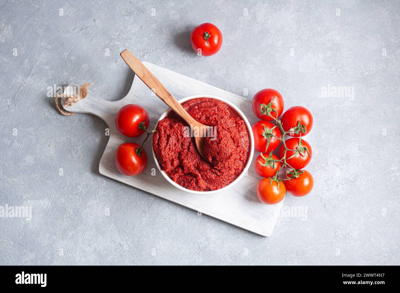 Pâte de tomate turque traditionnelle dans un bol avec des tomates fraîches sur une table rustique, nourriture saine maison Banque D'Images