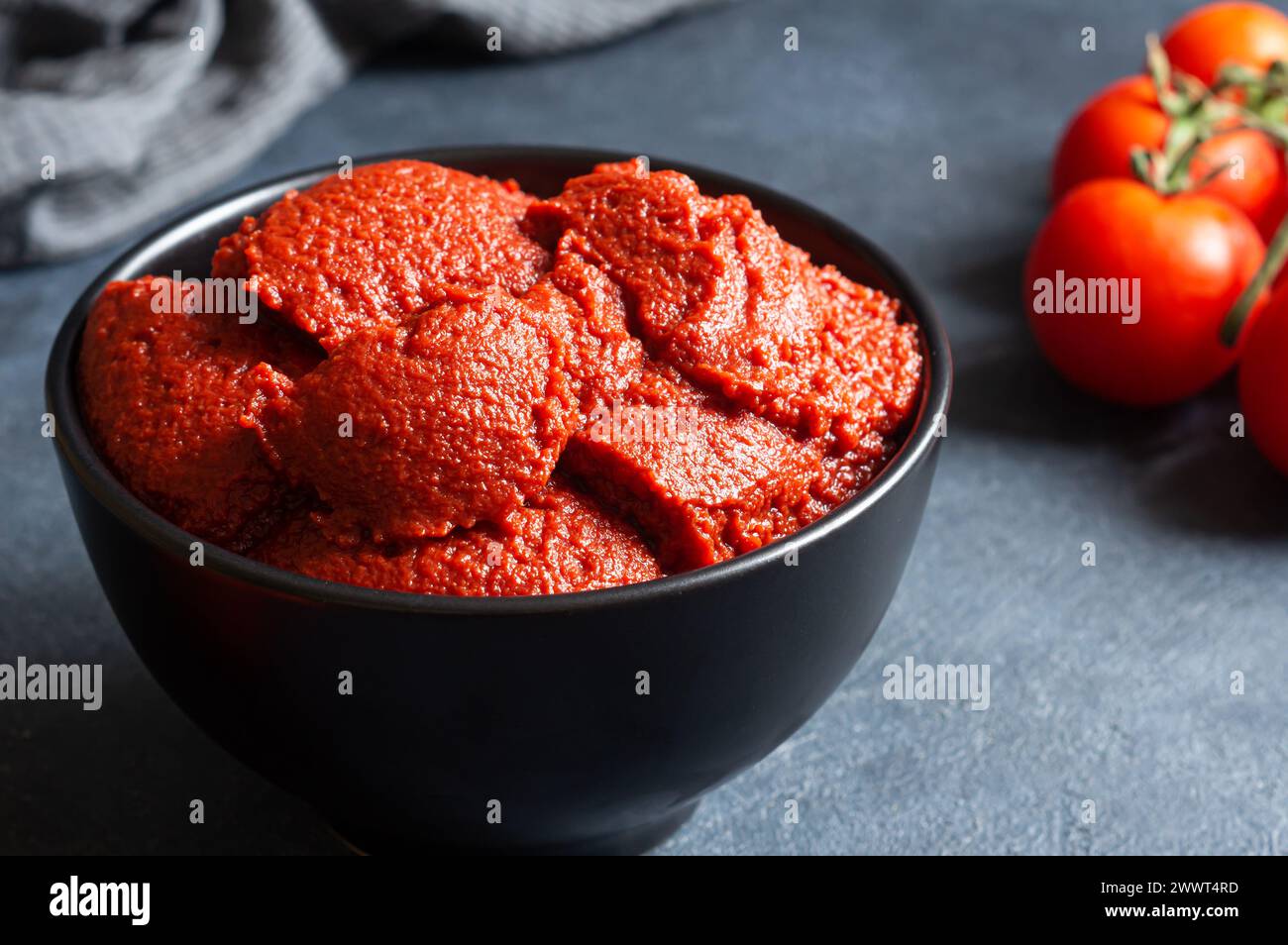 Pâte de tomate turque traditionnelle dans un bol avec des tomates fraîches sur une table rustique, nourriture saine maison Banque D'Images