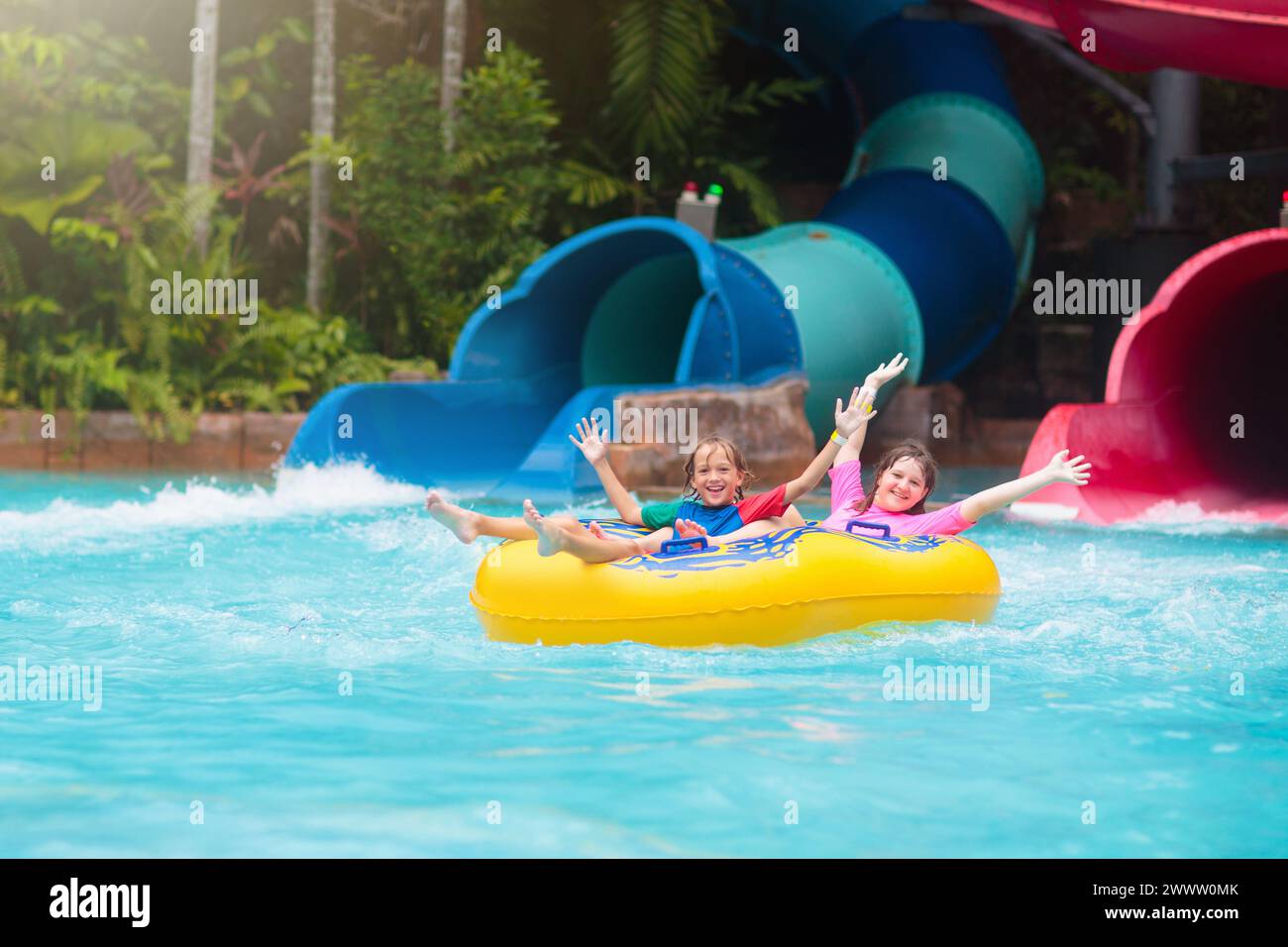 Enfants sur le toboggan aquatique dans la piscine extérieure. Famille dans un parc à thème aquatique. Les enfants s'amusent dans l'aire de jeux. Vacances d'été avec enfant. Banque D'Images
