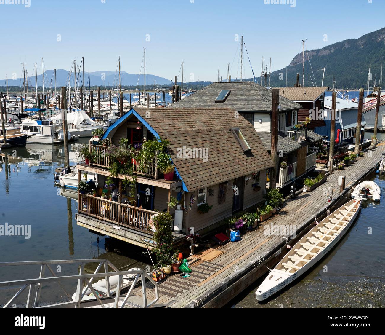 La marina de Cowichan Bay avec une maison flottante, un grand bateau à rames et des bateaux en arrière-plan Banque D'Images