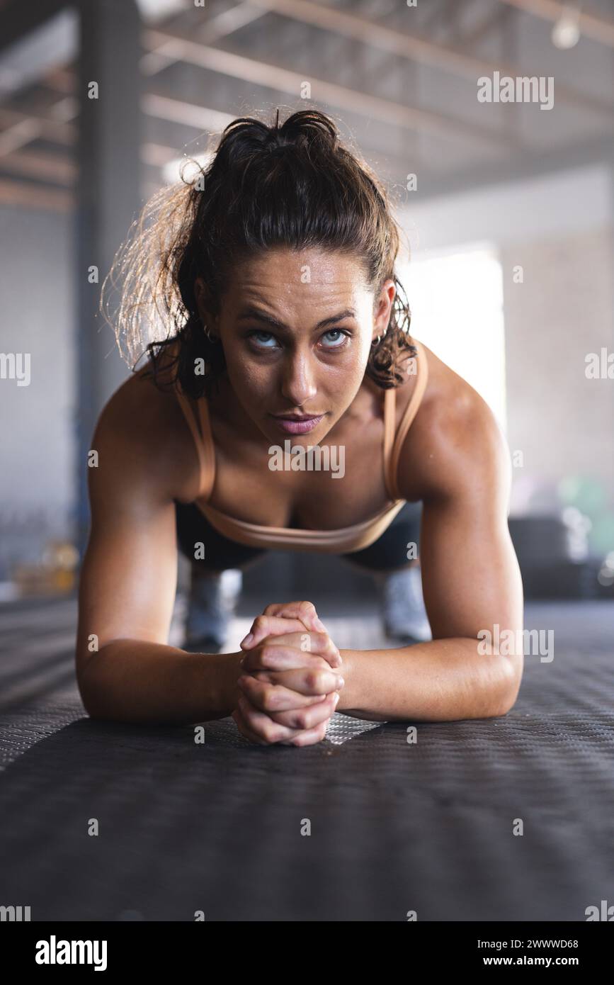 Une jeune femme caucasienne est concentrée sur son exercice de planche dans le gymnase Banque D'Images