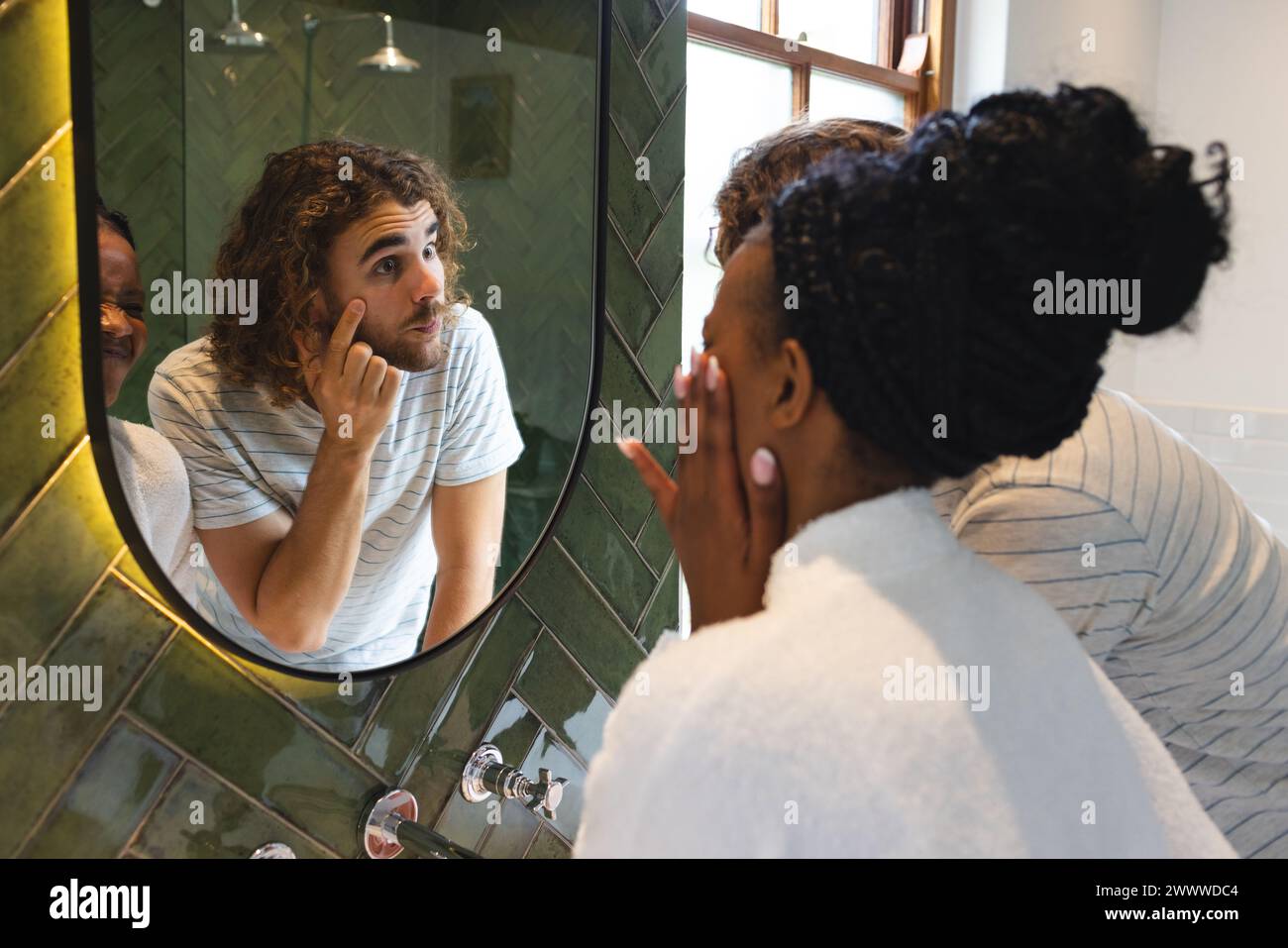 Un couple diversifié est dans la salle de bain faire leur routine de soins de la peau du matin Banque D'Images