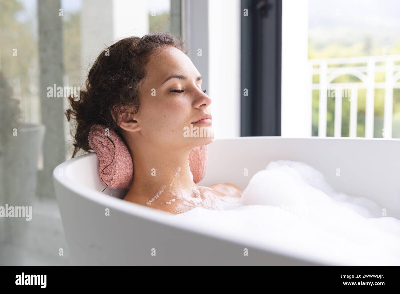 Jeune femme aime un bain relaxant à la maison, les yeux fermés Banque D'Images