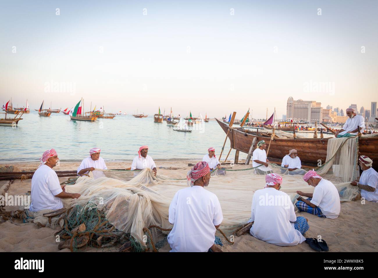 Pêcheurs arabes traditionnels assis à faire un filet à poissons sur la plage de katara. Banque D'Images