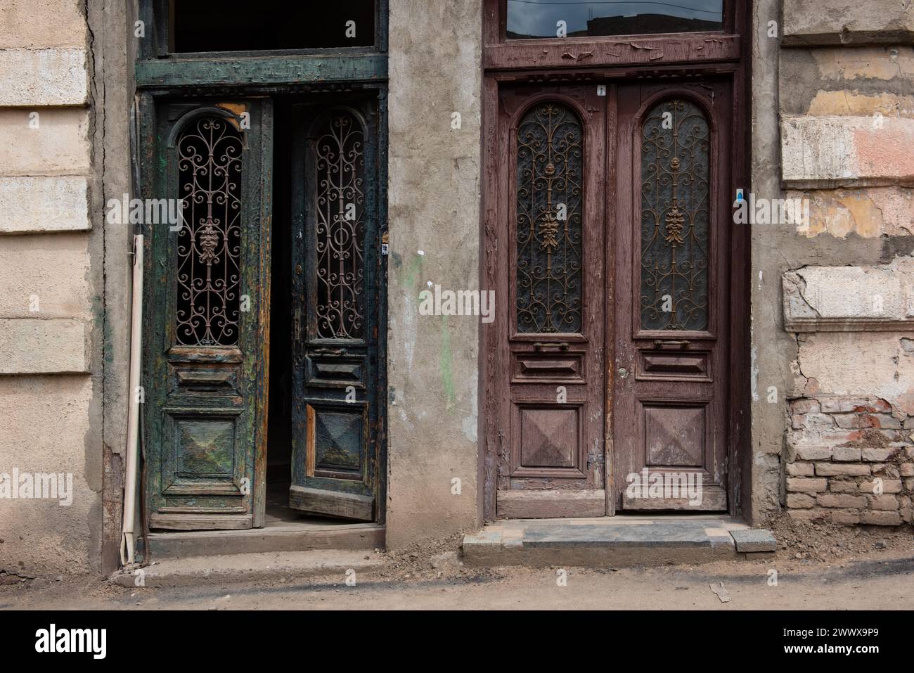 Vieilles portes en bois cassées à l'entrée d'un bâtiment condamné dans la vieille ville historique, une destination touristique populaire à Tbilissi, Géorgie. Banque D'Images