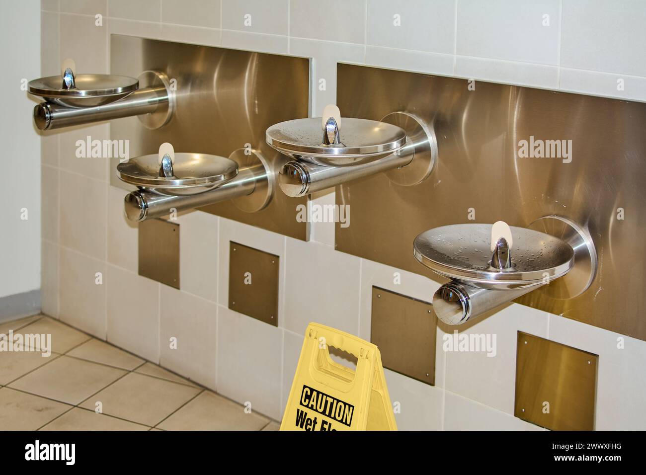 Image montrant un panneau d'avertissement dans une zone avec des fontaines d'eau potable, soulignant l'importance de la sécurité dans les espaces publics. Banque D'Images