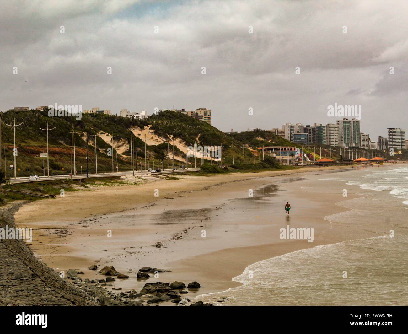 Praia do Calhau, Avenida Litoranea, dunes couvertes de végétation, bâtiments à l'horizon et ciel nuageux sur l'île de São Luis, Maranhão, Brésil Banque D'Images