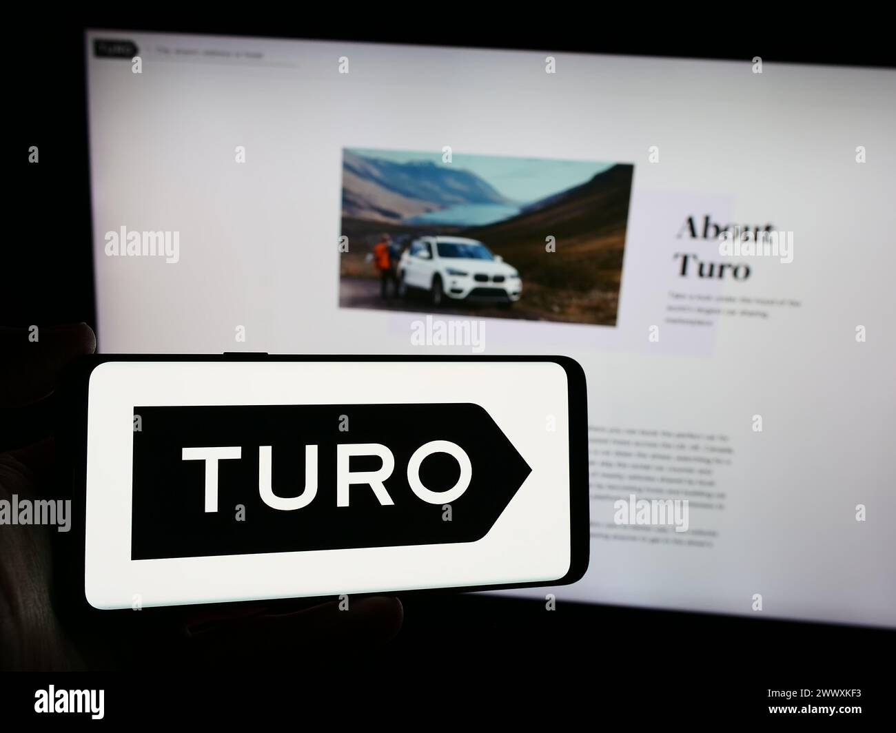 Personne tenant un smartphone avec le logo de la société américaine de partage de voiture peer-to-peer Turo Inc en face du site Web. Concentrez-vous sur l'affichage du téléphone. Banque D'Images