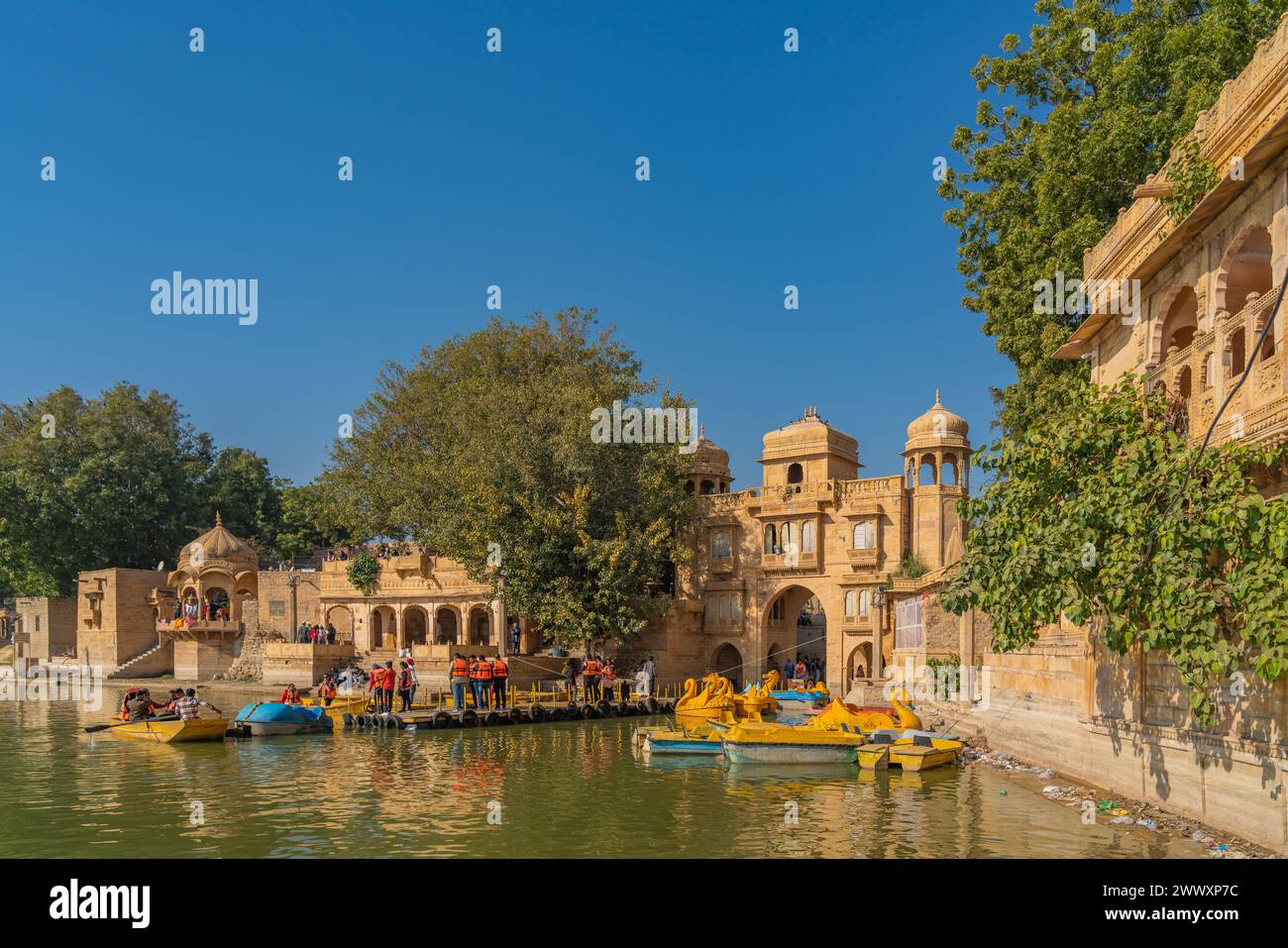 Jaisalmer, Inde - décembre 2023 : les gens pour la visite en bateau au lac Gadisar Jaisalmer Rajasthan avec le vieux temple en arrière-plan Banque D'Images