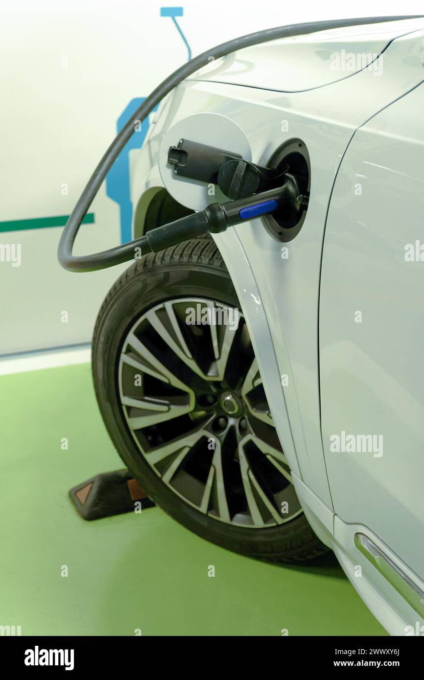 Voiture électrique blanche connectée au réseau à une borne de recharge dans un garage public Banque D'Images