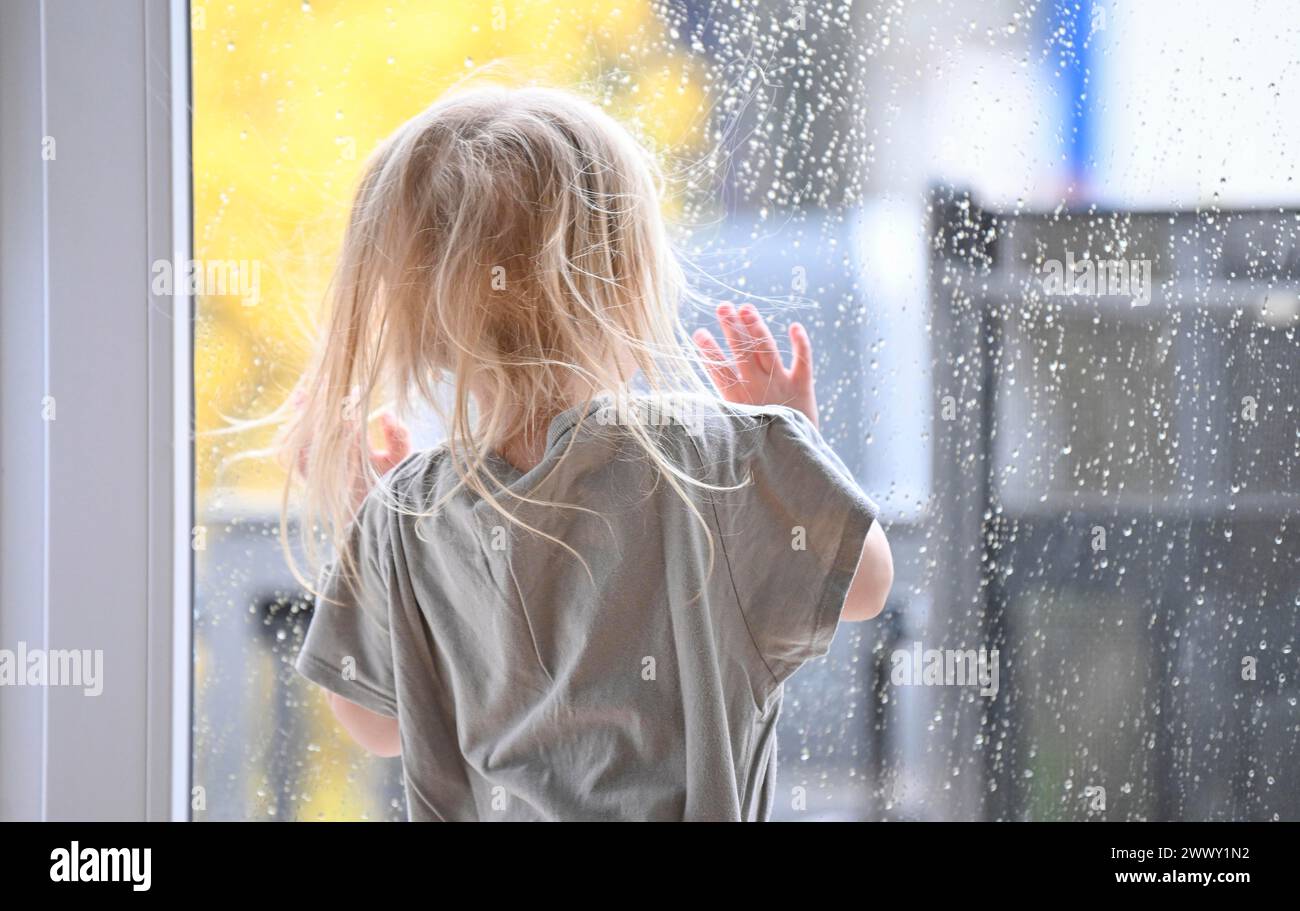 Petite fille, 2-3 ans, blonde, portrait, devant la fenêtre, regardant la pluie, gouttes de pluie sur la vitre, Stuttgart, Bade-Wuerttemberg, Allemagne Banque D'Images