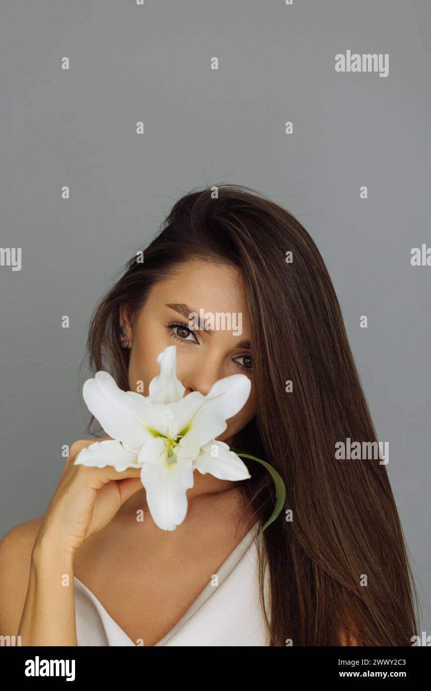 Femme mignonne avec fleur sur fond gris Banque D'Images