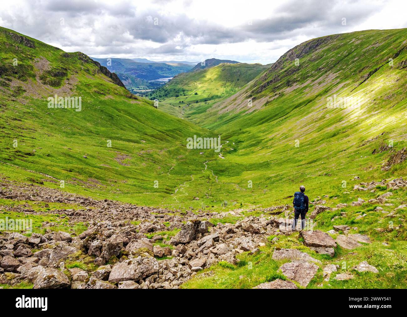 Walker descendant Threshthwaite Cove dans le fond des pâturages vers Hartsop et Patterdale et Ullswater dans le Cumbrian Lake District UK Banque D'Images