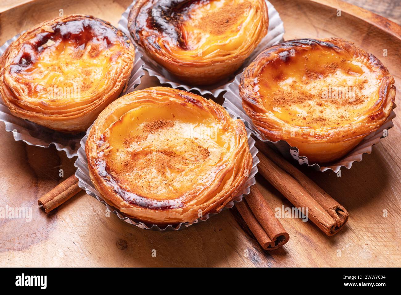 Tartes pastel de nata et bâtons de cannelle sur plateau en bois Vue de dessus. Banque D'Images