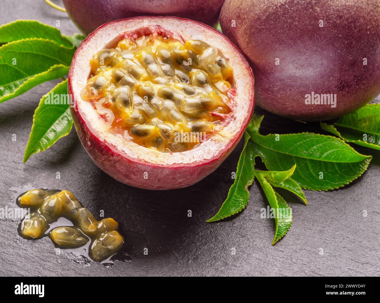Fruits de la passion violet foncé et la moitié des fruits maracuya isolés sur fond gris ardoise graphite. Banque D'Images