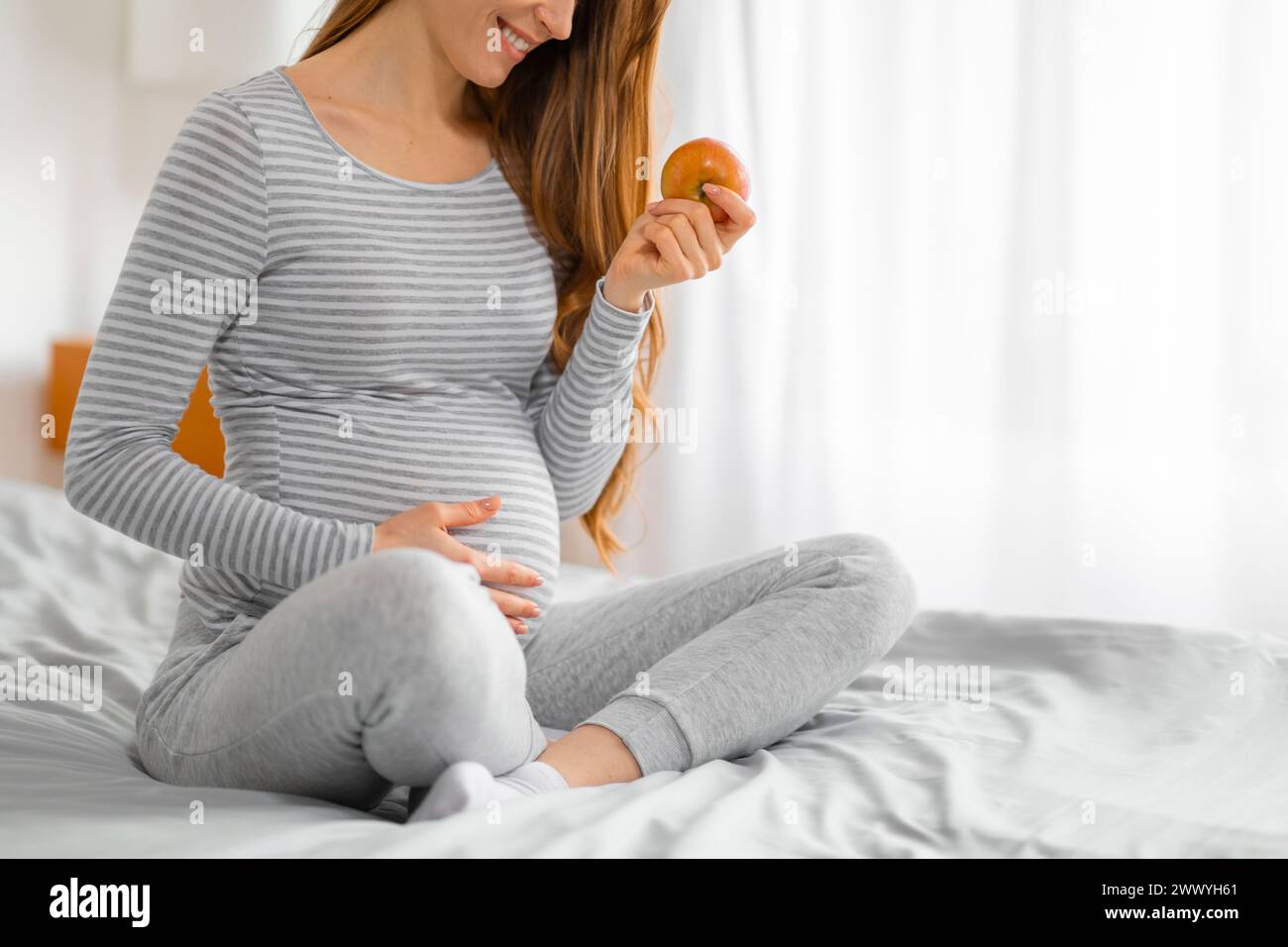 Femme enceinte contemplant une pomme dans sa main Banque D'Images