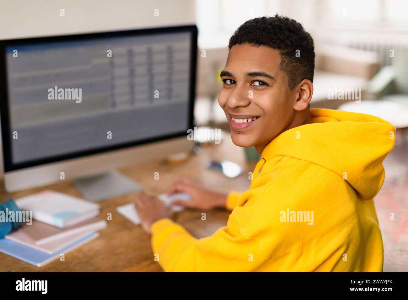 Adolescent noir joyeux avec ordinateur, souriant sur l'épaule Banque D'Images