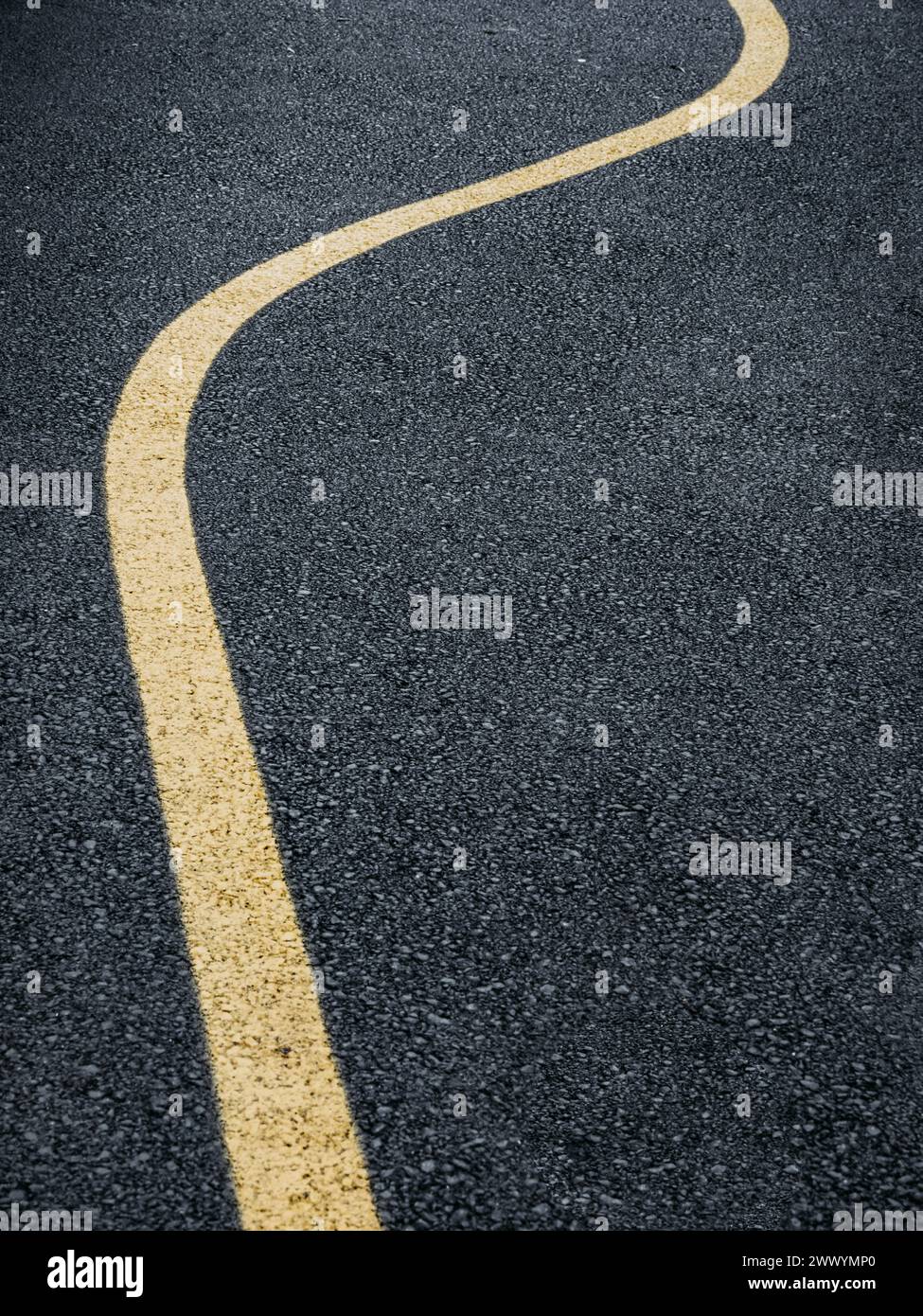 Une route en Suède avec une ligne courbe jaune vif peinte en bas du centre, guidant les véhicules le long de la chaussée lisse. Banque D'Images