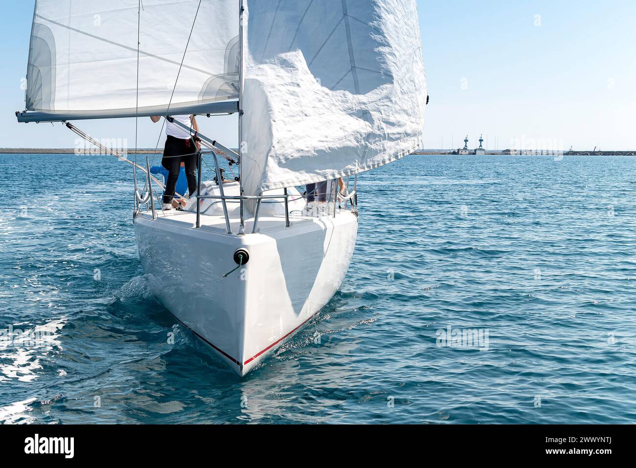 Un yacht élégant avec équipage embarque pour une course de régates, mettant en valeur le frisson de la voile dans la mer méditerranée claire Banque D'Images