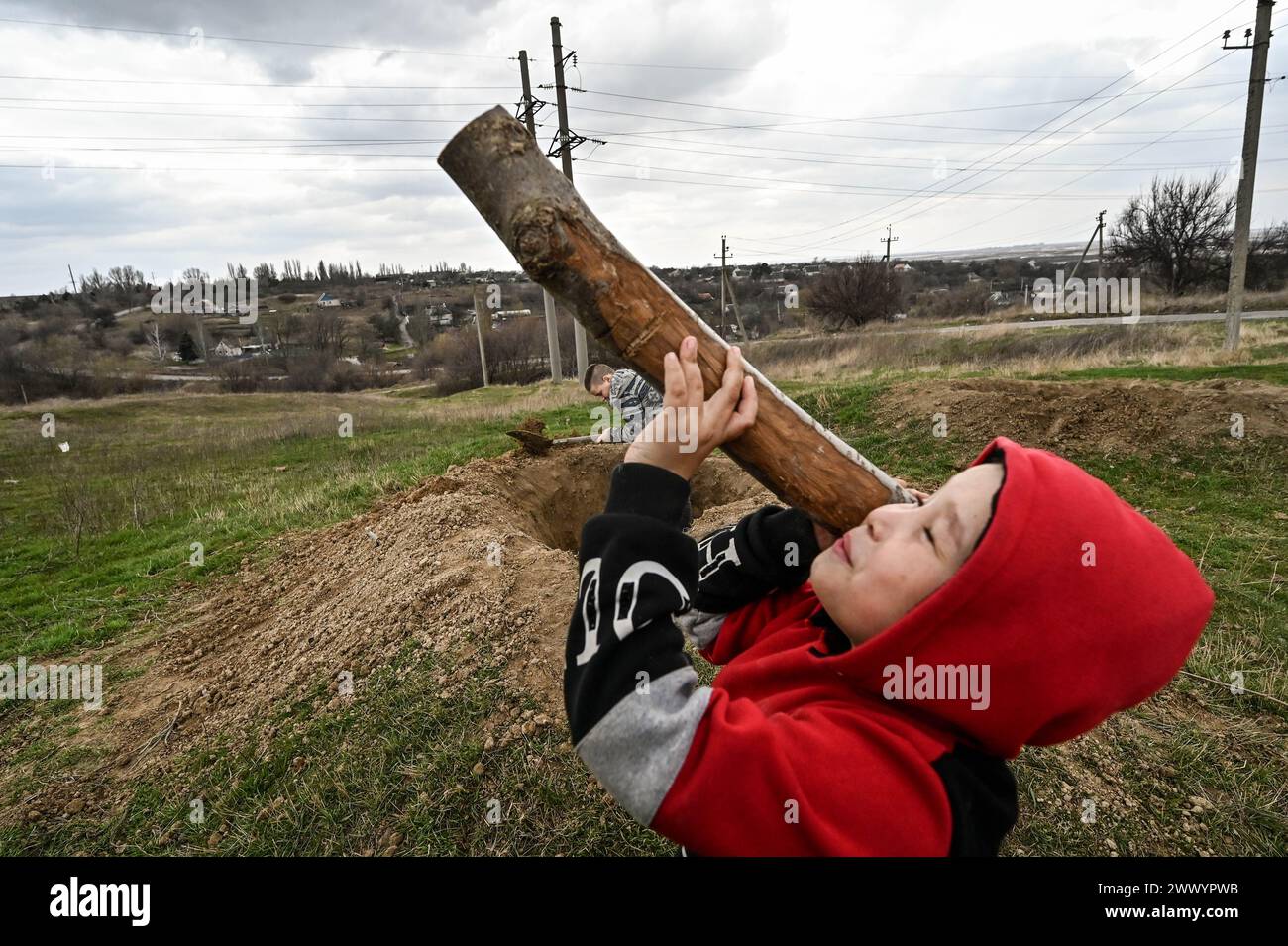 PRYMORSKE, UKRAINE - 20 MARS 2024 - Un garçon tient un bâton comme lanceur de RPG dans le village de première ligne de Prymorske, dans la région de Zaporizhzhia, dans le sud-est de l'Ukraine. Banque D'Images